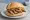 Broodje Steak: an illustration of beef, onion, mustard and butter on kaiser roll.