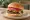 Burger Lebanese Style: an illustration of beef, garlic sauce, lettuce and tomato on burger bun.