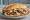 Carne Asada Fries Torta: an illustration of beef, cheese, potato, guacamole and more.