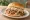 Carolina Whole Hog Sandwich: an illustration of pork, vinegar, pepper and coleslaw on burger bun.