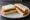 Cheese and Pickle: an illustration of cheddar cheese, pickle and butter on white bread.