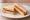 Cheese and Tomato: an illustration of cheddar cheese, tomato and butter on white bread.