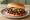 Chopped Beef Sandwich: an illustration of beef, pickle and onion on burger bun.