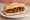 Choripán de Cancha: an illustration of pork, sausage and chimichurri on baguette.