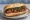 Chorizo Parrillero: an illustration of pork, sausage and chimichurri on baguette.