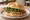 Cotoletta Sandwich con Rucola: an illustration of veal, egg, arugula and butter on kaiser roll.
