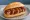 Currywurst extra scharf: an illustration of ketchup, curry powder and pepper on kaiser roll.