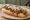 Detroit Coney Dog: an illustration of beef, pepper, mustard and onion on hot dog bun.