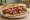 Döner Ekmek Arası: an illustration of beef, chicken, tomato, onion and more on bread.