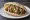 Falafel HaKosem Style: an illustration of chickpeas, tahini, tomato, cucumber and more on pita.