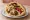Falafel Im HaKol (פלאפל עם הכל): an illustration of chickpeas, tahini, tomato, cucumber and more on pita.