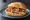 Finkenwerder Scholle Brötchen: an illustration of bacon and shrimp on bread.