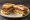 Fried Green Tomato BLT: an illustration of bacon, lettuce and mayonnaise on white bread.