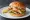 Geoduck Sandwich: an illustration of lettuce, tartar sauce and lemon on burger bun.