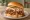 Georgia Peach BBQ Sandwich: an illustration of pork, coleslaw and pickle on burger bun.