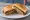 Goetta Sandwich: an illustration of pork, sausage, onion and mustard on white bread.