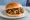 Gōngbǎo Jīdīng Hànbǎo (宫保鸡丁汉堡): an illustration of chicken, pepper, scallion, maggi seasoning sauce and more on burger bun.