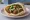 Gourmet Falafel (פלאפל גורמה): an illustration of falafel, hummus, tahini, tomato and more on pita.