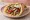 Gourmet Gyros: an illustration of pork, tzatziki, tomato, onion and more on pita.