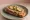 Grzanka z Pasztetem: an illustration of pork, pâté, butter and pickle on bread.