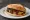 Guajolota de Mole: an illustration of brown sauce on telera roll.