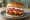 Gyros Burger: an illustration of beef, tomato, onion and tzatziki on burger bun.