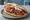Gyros im Fladenbrot: an illustration of pork, tomato, onion, tzatziki and more.