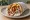 Gyros Kotopoulo se Pita: an illustration of chicken, tomato, onion, tzatziki and more on pita.