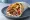 Gyros Miktós (Γύρος Μικτός): an illustration of pork, chicken, tomato, onion and more on pita.