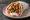 Gyros - Northern Greece Style: an illustration of pork, tomato, onion, tzatziki and more on pita.