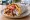 Gyros - Piraeus Style: an illustration of pork, chicken, tomato, onion and more on pita.