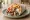 Gyros Thessalonikis: an illustration of pork, chicken, tzatziki, tomato and more on pita.