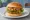 Hamburger Wegetariański: an illustration of lettuce, tomato and onion on burger bun.