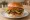 Hamburger z Boczkiem: an illustration of beef, bacon, lettuce, tomato and more on burger bun.
