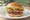 Hamburguesa Casera: an illustration of beef, lettuce, tomato and onion on burger bun.