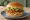 Hamburguesa de Pollo: an illustration of chicken, lettuce, tomato and mayonnaise on burger bun.