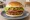 Hamburguesa Vegetariana: an illustration of lettuce, tomato and onion on burger bun.