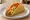 Hard Taco (USA): an illustration of beef, cheese, lettuce, tomato and more on tortilla.