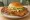 Hoosier Tenderloin: an illustration of pork, egg, lettuce, tomato and more on burger bun.