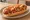 Hot Dog de Carreta: an illustration of sausage, onion, tomato, mayonnaise and more on hot dog bun.