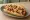 Hot Dog Hawaiano: an illustration of sausage and pineapple on hot dog bun.