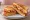 Isaac Toast — Bacon Potato Pizza Toast: an illustration of bacon, hash browns, mozzarella and butter on white bread.