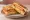 Isaac Toast — Ham Cheese Potato Toast: an illustration of ham, egg, cheddar cheese, hash browns and more on white bread.