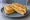 Isaac Toast — Ham Cheese Toast: an illustration of ham, egg, cheddar cheese, corn and more on white bread.