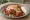İskender Kaşarlı: an illustration of lamb, beef, marinara, butter and more on pita.