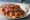 İskender Porsiyon: an illustration of lamb, beef, marinara, butter and more on pita.