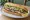 İstavrit Ekmek: an illustration of fish, onion, lettuce and lemon on bread.