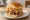 Kalua Pork Sandwich: an illustration of pork, coleslaw, pineapple and sriracha.