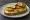 Kanapka Wegetariańska: an illustration of butter, cheese, tomato, cucumber and more on bread.