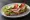 Kanapka z Kurczakiem Wędzonym: an illustration of butter, chicken, lettuce, tomato and more on bread.